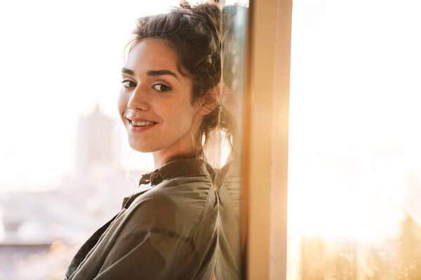 Изображение элегантной брюнетки, улыбающейся женщине, стоящей над стеклянной дверью
