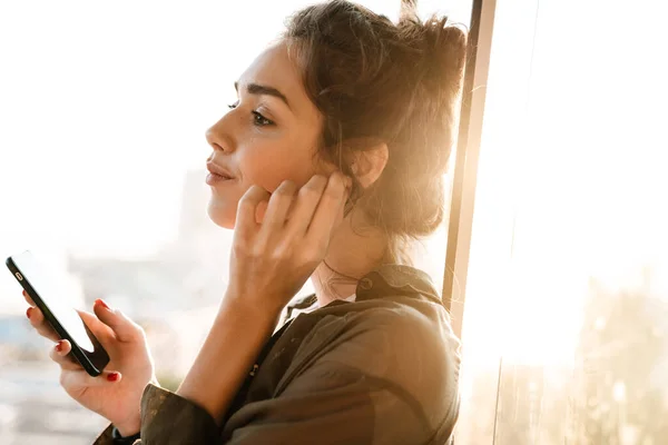 Beeld van mooie vrouw in oordoppen houden smartphone op terras o — Stockfoto