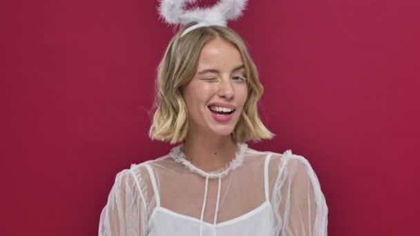 カーニバルの衣装を着たかなり天使の女性がカメラに勝利し 赤い壁の背景に隔離された笑顔 — ストック動画
