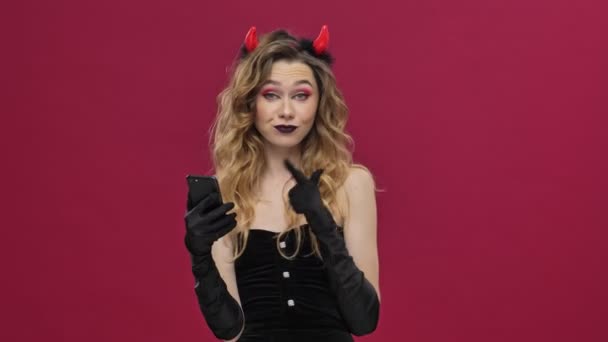 Coquettish Diable Femme Costume Carnaval Souriant Pointant Doigt Son Smartphone — Video