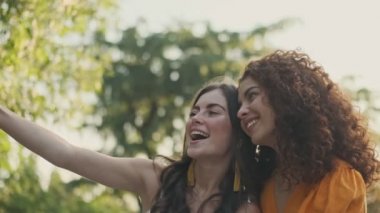 Güzel, mutlu, genç kızlar parkta otururken fotoğraf çektirip eğleniyorlar.