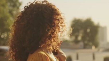 Back view of happy cute young girls friends holding cups of takeaway coffee and looking at the sunrise while standing outdoors at the street