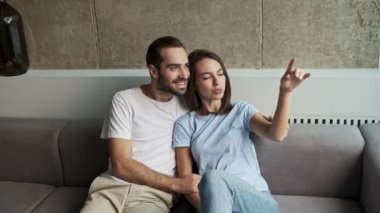 Güzel, mutlu, genç bir çift. Evdeki kanepede oturup pencereye bakarken sarılıp sohbet ediyorlar.