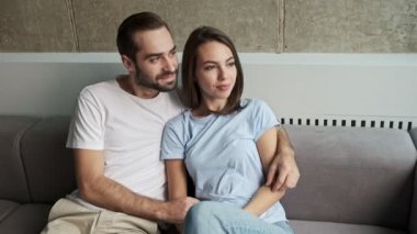 Yakışıklı, gülümseyen, sevimli bir çift. Evdeki kanepede otururken birbirlerine sarılıp sohbet ediyorlar.