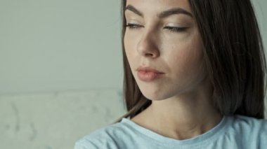 Çekici, ciddi, esmer bir kadının yan tarafa bakıp evde dinlenirken mutlu oluşunun yakın görüntüsü.