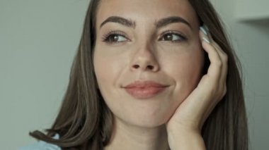 Cropped view of attractive calm young brunette woman smiling and looking at the side while sitting at home