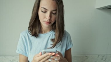 Güzel, ciddi, esmer bir kadın akıllı telefon kullanıyor ve birinden rahatsız edici bir telefon alıyor ama evde otururken mutlu oluyor.