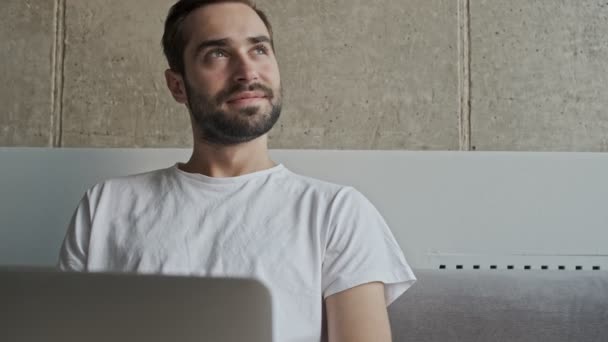 Bonito Pensativo Jovem Morena Homem Sorrindo Conversando Laptop Enquanto Sentado — Vídeo de Stock