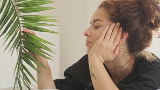 Pensativo Hermosa Joven Pelirroja Bata Seda Mirando Atentamente Planta Verde — Vídeos de Stock