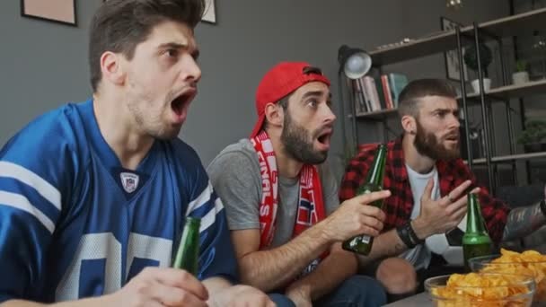 Trzech Zszokowanych Fanów Piłki Nożnej Zdumiewa Coś Otwartymi Ustami Siedząc — Wideo stockowe