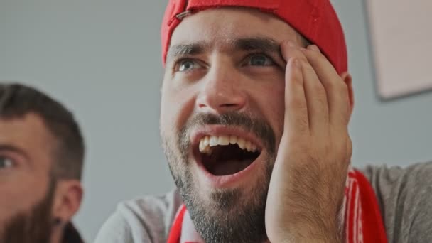 Zaskoczony Brodaty Męski Fan Noszenia Czapki Radując Się Krzycząc Siedząc — Wideo stockowe