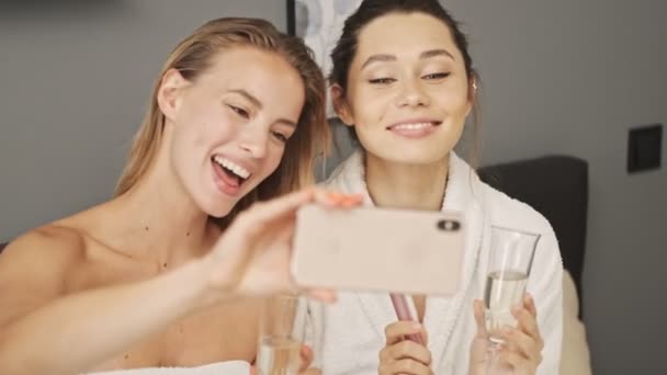 Två Skönhetsnöjda Tjejer Som Gör Selfie Smartphone Medan Dricker Champagne — Stockvideo