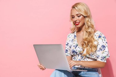 Sandalyede otururken gümüş dizüstü bilgisayar kullanan güzel bir kadın görüntüsü