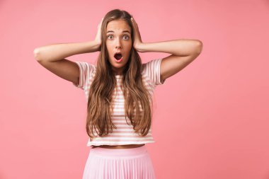 Şaşırmış genç bir kız pembe duvar arkasında yalnız poz veriyor..