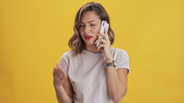Kırmızı Dudaklı Hoşnutsuz Genç Kadın Sarı Arka Planda Cep Telefonuyla — Stok video