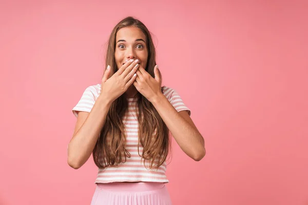 Αισιόδοξη νεαρή κοπέλα θέτει απομονωμένη πάνω από ροζ τοίχο φόντο που καλύπτει το στόμα. — Φωτογραφία Αρχείου