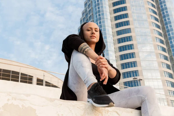 Image of bold bald woman using cellphone while sitting