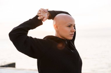 Güzel kel bir kadının görüntüsü ileriye bakıyor ve kollarını açıyor.