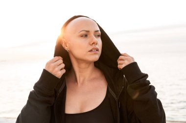 Siyah başlıklı genç ve kel bir kadının görüntüsü.