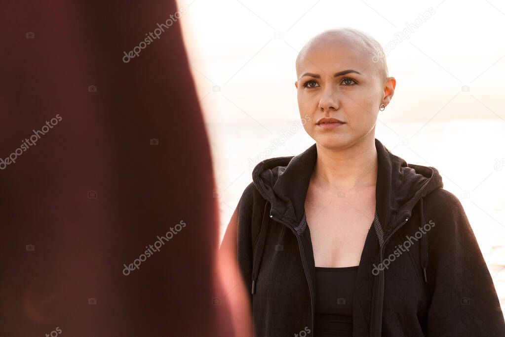 Image of focused bald woman looking forward in sunny morning outdoors