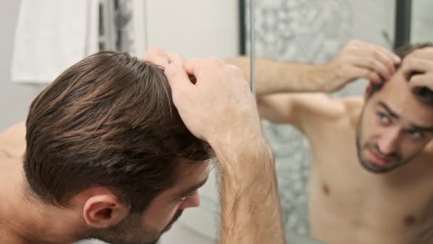 在浴室里看着镜子的时候 可以近距离观察到不快乐的 英俊的 没有胡子的 没穿衬衫的年轻人的头发有些问题 — 图库视频影像