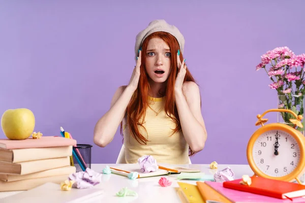 Photo d'une étudiante choquée attrapant sa tête assise au bureau avec des livres — Photo