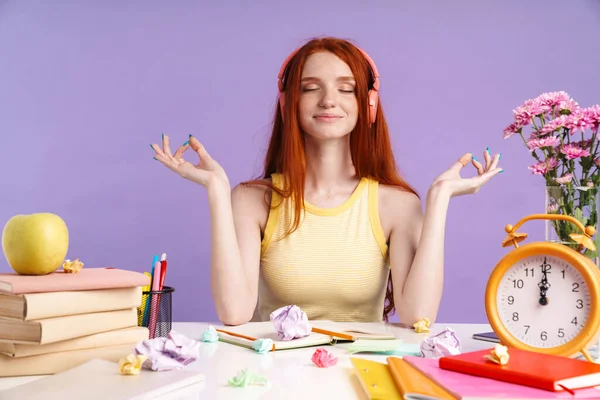 Foto van een ontspannen student meisje in een hoofdtelefoon aan het bureau met oefenboeken — Stockfoto