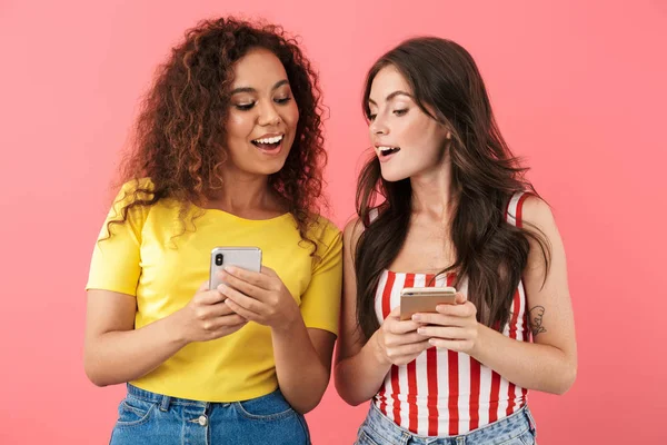 Gambar gadis-gadis multinasional muda tersenyum dan melihat ponsel — Stok Foto