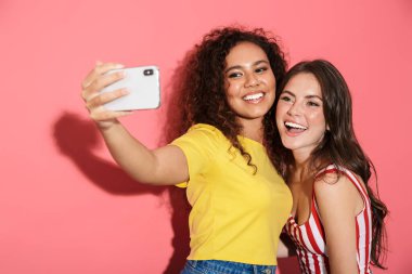 Cep telefonuyla selfie çeken neşeli çokuluslu kızlar.