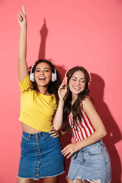 Imagem de meninas multinacionais otimistas ouvindo música com fones de ouvido — Fotografia de Stock