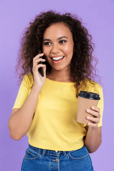 Image of young african american woman holding coffee cup and talking on smartphone — Stock Photo, Image