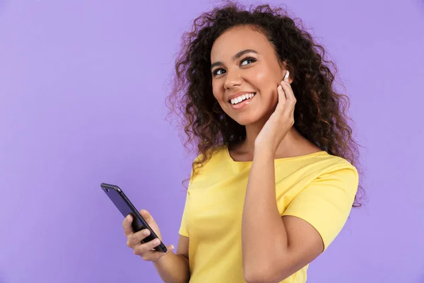 Image of charming african american woman listening to music with earpods — Stock Photo, Image