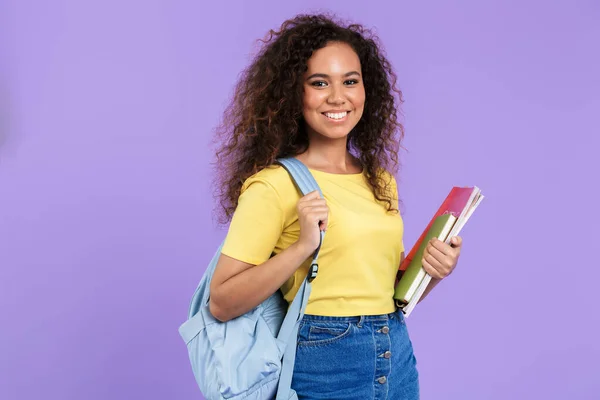 Imagen de la alegre estudiante afroamericana sosteniendo libros de ejercicios — Foto de Stock