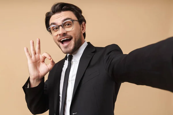 Obraz radosnego biznesmena pokazującego znak ok podczas robienia selfie — Zdjęcie stockowe