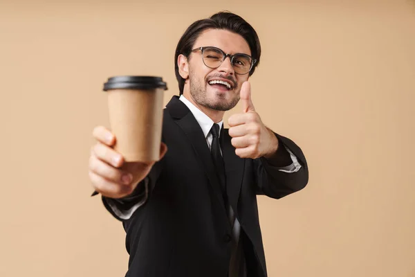 Bild av ung affärsman som visar tummen upp och håller kaffe c — Stockfoto