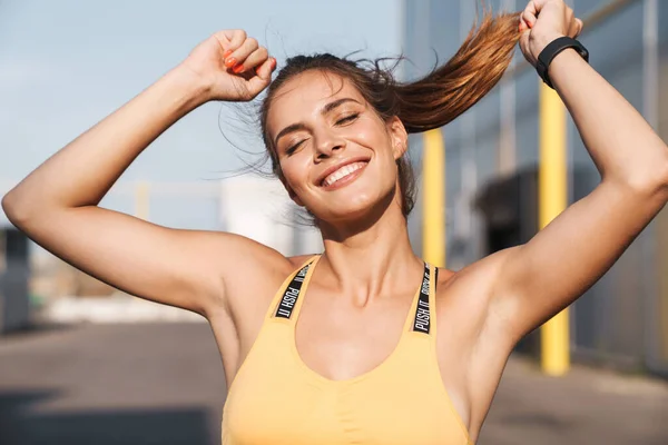 Image de femme heureuse en vêtements de sport souriant et marchant à l'extérieur — Photo