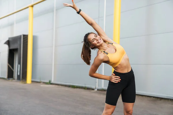 Imagen de mujer alegre en ropa deportiva sonriendo y haciendo ejercicio ou — Foto de Stock