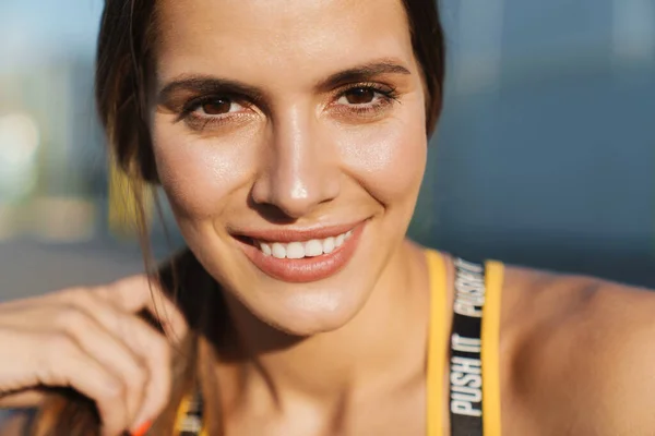 Beeld van een aantrekkelijke vrouw in sportkleding glimlachen tijdens het wandelen ou — Stockfoto