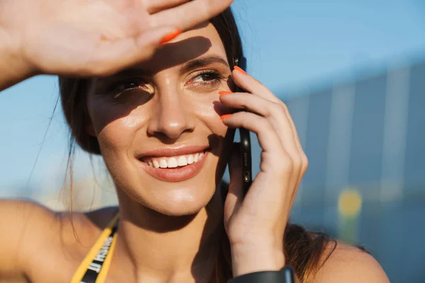 Bilde av en glad kvinne som snakker i mobiltelefon mens hun står utadvendt – stockfoto