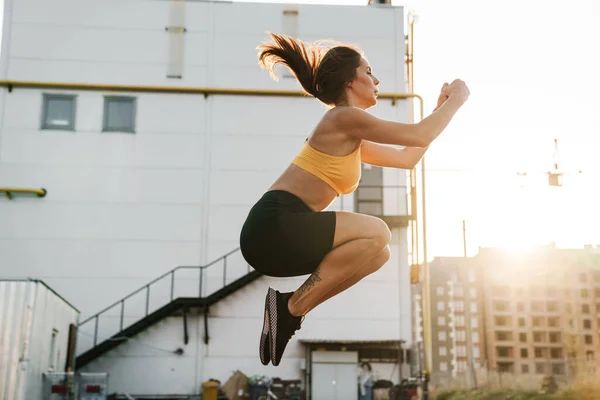 Imagem de mulher em sportswear saltar enquanto fazendo crunches outdoo — Fotografia de Stock