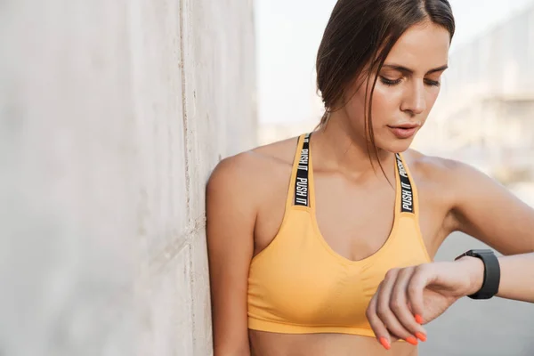 Imagen de la mujer en ropa deportiva mirando smartwatch mientras camina —  Fotos de Stock