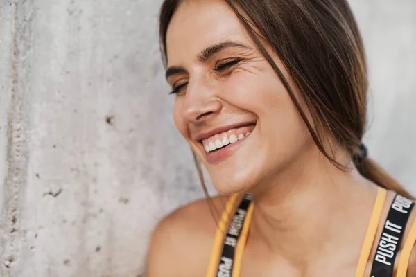 Image d'une femme heureuse souriante debout au-dessus d'un mur de béton o — Photo