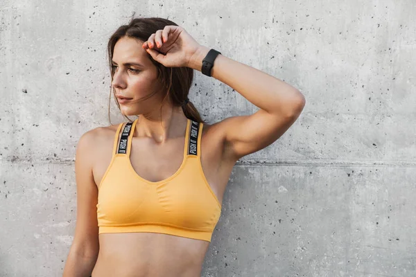 Imagen de la mujer en ropa deportiva de pie sobre pared de hormigón al aire libre — Foto de Stock