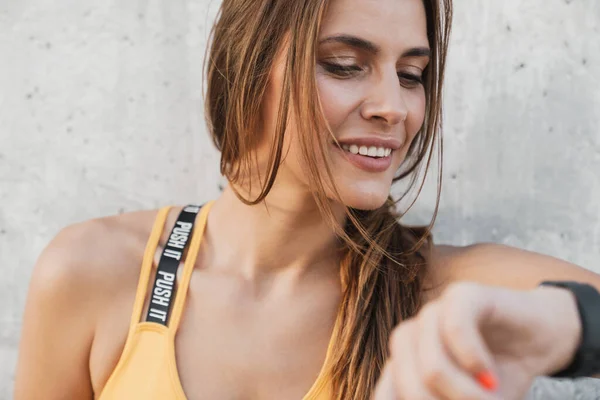 Bilde av brunettkvinne som smiler og ser på armbåndsur-utdoo – stockfoto