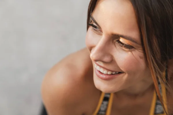 Image closeup of smiling woman looking aside over concrete wall — Stock Photo, Image