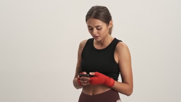 Sorrindo Mulher Desportiva Vestindo Traje Treino Usando Smartphone Isolado Sobre — Vídeo de Stock