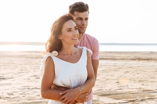 Belo jovem casal vestindo roupas de verão em pé na praia — Fotografia de Stock