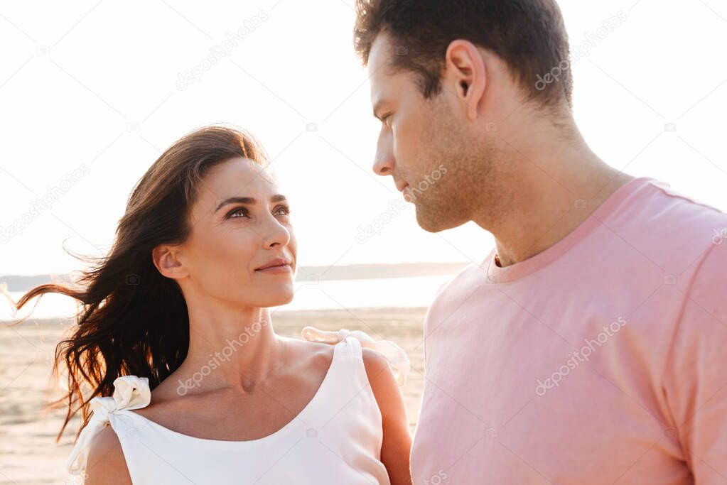 Beautiful young couple wearing summer clothing standing at the beach