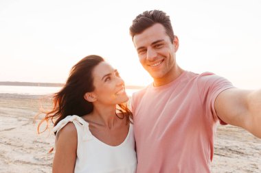 Yazlık giysiler giyen genç ve güzel bir çift sahilde dikiliyor.