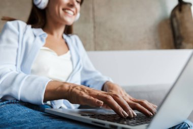 Evdeki kadın oturma odasında dizüstü bilgisayar kullanıyor..